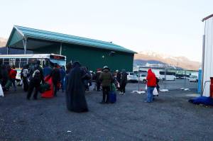 People staying at the citys cold weather emergency shelter during its final night of operation board a bus bound for the Glory Hall and other locations in town early Tuesday morning. In the background are tour buses that a company says were broken into and damaged during the winter by people staying at the shelter, and one of the first cruise ships of the season. (Mark Sabbatini / Juneau Empire)