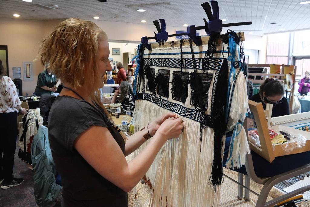 Annemarie Hasskamp, a Skagway resident, works to finish a kid-sized Ravenstail robe at a weavers gathering Tuesday at Centennial Hall a few hours before a ceremony featuring the robes. (Mark Sabbatini / Juneau Empire)