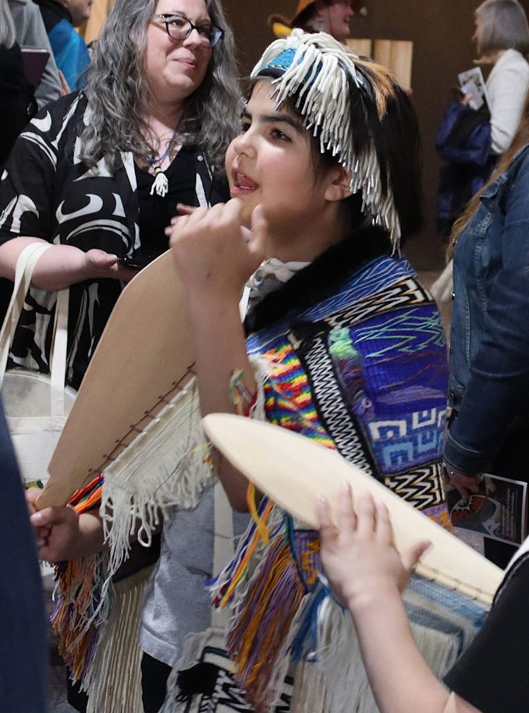 Aurora Southerland, 11, wears an unusually bright multicolor Ravenstail robe for a ceremony Tuesday evening at Centennial Hall highlighting the history and works of the technique. (Mark Sabbatini / Juneau Empire)