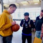 Thunder Mountain High School seniors James Polasky signs a basketball for a fan as senior Sam Lockhart and teammates look on before Polasky and Lockhart signed letters of intent on Thursday in the TMHS commons to play college basketball. Polasky will attend St. Olaf in Minnesota and Lockhart will attend Edmonds College in Washington state. (Klas Stolpe / For the Juneau Empire)