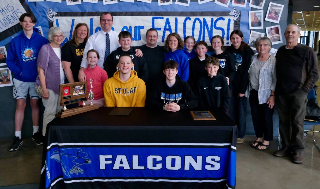 James Polasky, left, and Samuel Lockhart, right, pose with their families after signing letters of intent on Thursday in the TMHS commons to play college basketball. Polasky will attend St. Olaf in Minnesota and Lockhart will attend Edmonds College in Washington state. (Klas Stolpe / For the Juneau Empire)