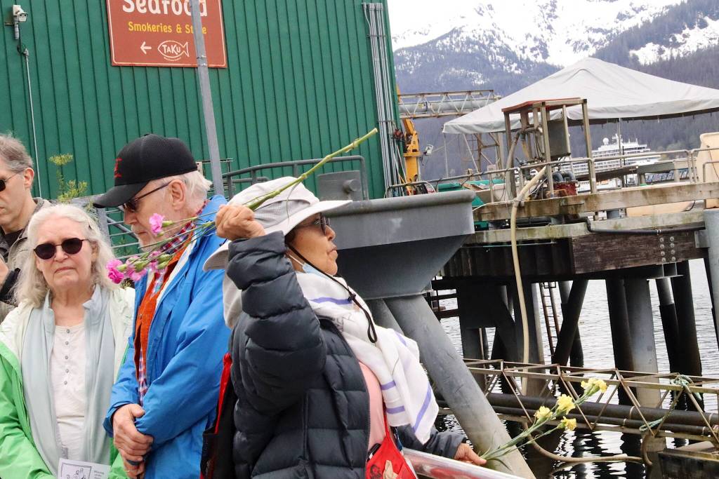 A woman casts flowers into the sea from dock next to the Alaska Commercial Fishermens Memorial during the annual reading of names on the memorial and Blessing of the Fleet on Saturday morning. (Mark Sabbatini / Juneau Empire)