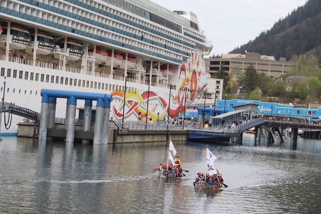 Two canoes paddled by members of the One People Canoe Society are dwarfed by a cruise ship as they near their landing spot during the annual Juneau Maritime Festival at Elizabeth Peratrovich Plaza on Saturday. (Mark Sabbatini / Juneau Empire)