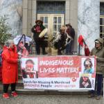 Advocates on behalf of missing and murdered Indigenous persons hold a banner and perform a opening song during a rally in front of the Alaska State Capitol on Sunday to commemorate the annual Missing and Murdered Indigenous Persons Awareness Day. (Mark Sabbatini / Juneau Empire)