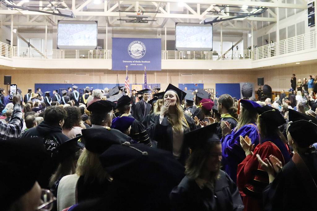 A newly graduated University of Alaska Southeast student blows a kiss toward the crowd as the students exit Sundays commencement ceremony to congratulations from university professors and other leaders along both sides of the center isle. (Mark Sabbatini / Juneau Empire)