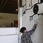 Zack Andrews, who said he visits Pipeline Skate Park about three time a week, paints over a mural at the entrance on Saturday. (Mark Sabbatini / Juneau Empire)