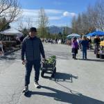 Silver Ligsay brought his own garden wagon to haul his new vegetables home. He purchased tomatoes, zucchini, bok choy and kale. He is both gardener and cook for his family. (Laurie Craig / Juneau Empire)