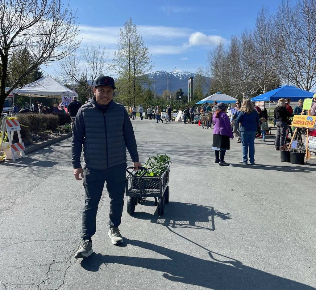 Silver Ligsay brought his own garden wagon to haul his new vegetables home. He purchased tomatoes, zucchini, bok choy and kale. He is both gardener and cook for his family. (Laurie Craig / Juneau Empire)