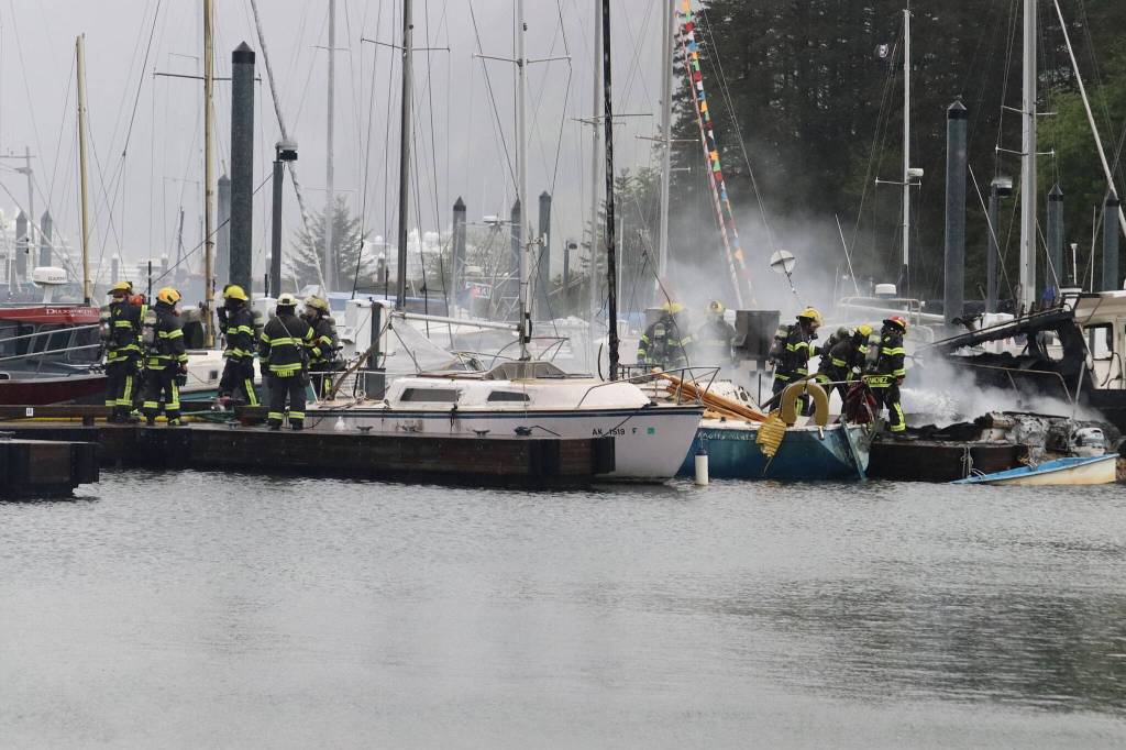 Capital City Fire/Rescue firefighters work to contain a fire that spread to three boats in Douglas Harbor on Monday evening. (Mark Sabbatini / Juneau Empire)