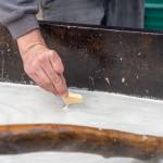 Ted Hart dips Pilot Bread into the warming eulachon oil on May 2. (Lex Treinen/Chilkat Valley News)