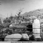 A woman lies on a gravestone in the city section of the Douglas cemetery circa 1910-1915. (Alaska State Library, P162-150, Ed Andrews Collection)