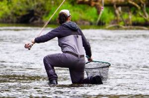 The authors wife kneels to net a trout over the weekend. (Photo by Jeff Lund)