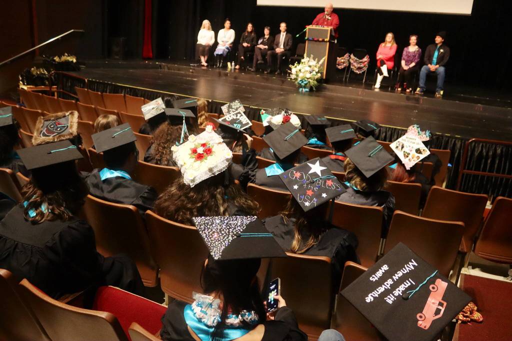 The custom-decorated caps of some of the 31 students graduating from Yaaḵoosgé Daakahídi High School are seen at the commencement ceremony Sunday in the Juneau-Douglas High School: Yadaa.at Kalé auditorium. (Mark Sabbatini / Juneau Empire)
