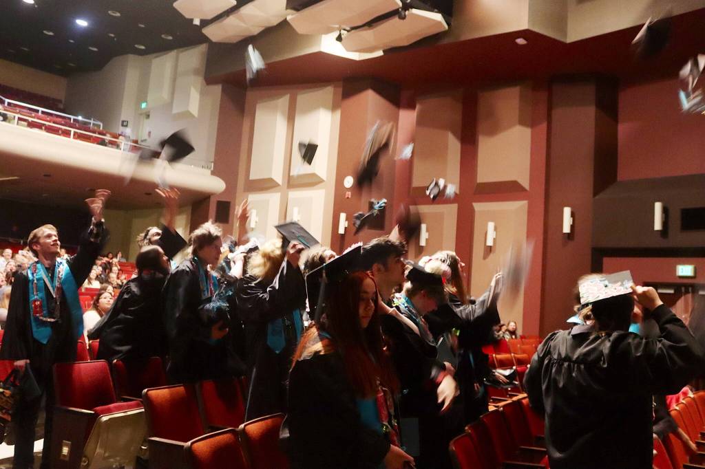 Newly graduated students at Yaaḵoosgé Daakahídi High School toss their caps in the air following Sundays commencement ceremony in the Juneau-Douglas High School: Yadaa.at Kalé auditorium. (Mark Sabbatini / Juneau Empire)