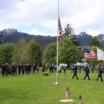 Veterans, families and others salute the entrance of a color guard during a Memorial Day ceremony at Evergreen Cemetery on Monday. (Mark Sabbatini / Juneau Empire)