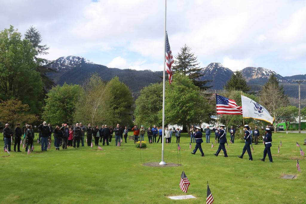Veterans, families and others salute the entrance of a color guard during a Memorial Day ceremony at Evergreen Cemetery on Monday. (Mark Sabbatini / Juneau Empire)