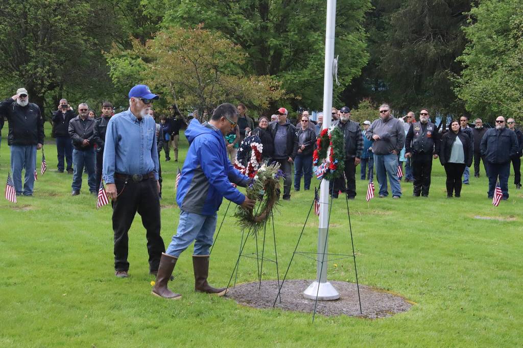 Lai Hinckle (right) and Keith Wertheimer place a wreath from the Juneau Elks Lodge 420 at the base of the flagpole at Evergreen Cemetery during a Memorial Day ceremony Monday. (Mark Sabbatini / Juneau Empire)