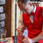 Juneau author W.R. Kozey signs a copy of his book Tall Tales of Alaska, The Red Dog Saloon: Stories from the Gold Rush & More at his first signing event on Sunday. (Jasz Garrett / Juneau Empire)