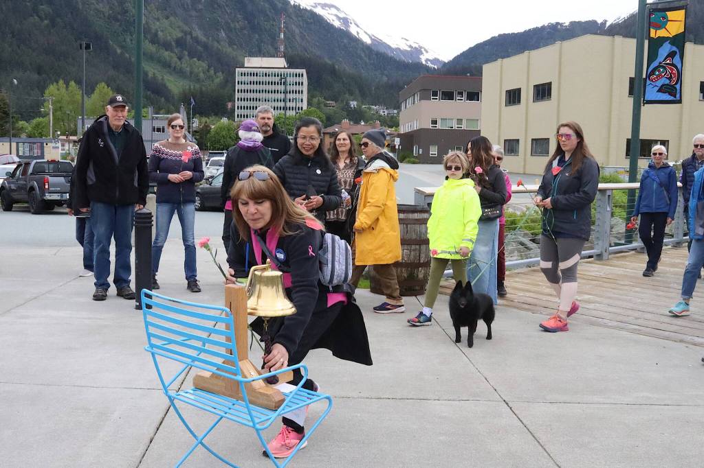 Angela Miller, diagnosed with breast cancer in 2017 and 2021, rings a bell similar to one patients ring at the completion of their treatment during the annual Celebration of Life Walk from Marine Park to Bill Overstreet Park on Sunday. (Mark Sabbatini / Juneau Empire)