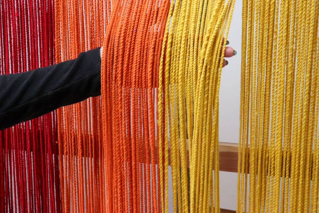 Melina Meyer shows the difference in the Ravenstail warp. Where youth began to learn to weave the warp is loosely braided; where a mentor wove its tight. (Jasz Garrett / Juneau Empire)