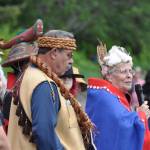 Siekoonie Fran Houston (right, with microphone), spokesperson for the Aakw Kwaan people, welcomes traditional Tlingit canoes to the Auke Bay beach at the site of the former village which was home to her people for generations. Houston, of the Raven moiety, is joined by Yaanishtuk Mike Tagaban, an Eagle moiety leader and Xunei Lance Twitchell (far left). Wearing a Shark Clan hat is Naomi Michaelson. (Laurie Craig / Juneau Empire)