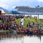 Canoes from communities south of Juneau led by the One People Canoe Society land downtown on Tuesday to cheers and songs from people on shore. (Jasz Garrett / Juneau Empire)