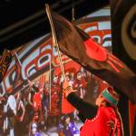 Jamiann Hasselquist waves the flag for Murdered and Missing Indigenous People at Grand Entrance. (Jasz Garrett / Juneau Empire)