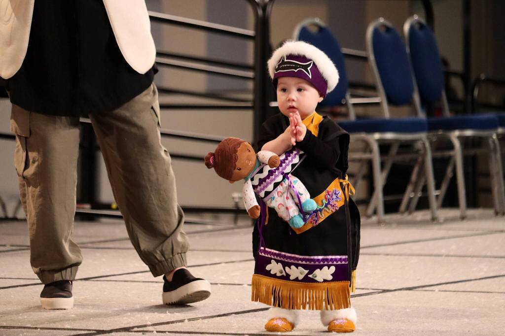 Tayana Copper-Jan Cavan Adamek, 14 months old, is escorted by her mother Kluane Adamek during the toddler regalia review as part of Celebration on Thursday at Centennial Hall. (Mark Sabbatini / Juneau Empire)