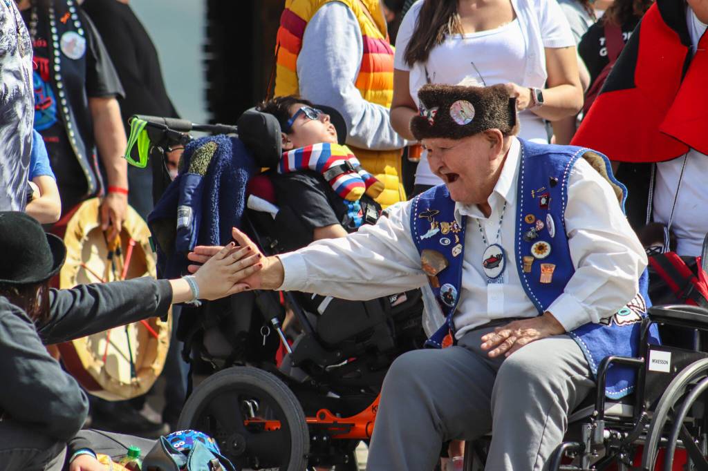 Ninety-year-old Herman Davis, the speaker of the Coho Clan, shakes hands as he participates in the parade. (Jasz Garrett / Juneau Empire)