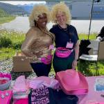 Dolly Parton look-alikes Raineka Ackley and Emily Thompson from the Southeast Alaska Association for the Education of Young Children set the mood for the organizations first annual Dolly Dash Fun Run on Saturday by wearing fluffy blonde wigs and costume enhancements. Country singer Parton created a reading program called the Imagination Library that mails free books monthly to children ages newborn to five years. The race registration table offers some of the race swag. (Laurie Craig / Juneau Empire)