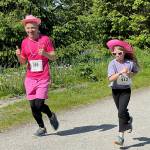 In the spirit of Dolly Partons country music roots, race participant Mendenhall River Community School Principal Eric Filardi runs in costume with young Lucy Vogel wearing heart-shaped sunglasses as they enjoy the sunny Saturday weather on the Airport Dike Trail race course. About 85 runners participated, many wearing pearls and pink hats provided at the starting tent. (Laurie Craig / Juneau Empire)