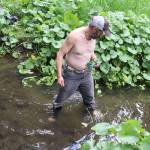 Garrett Derr bathes in a stream filled with coins tossed by people from a nearby footbridge along a path near Juneau International Airport on Sunday. (Mark Sabbatini / Juneau Empire)