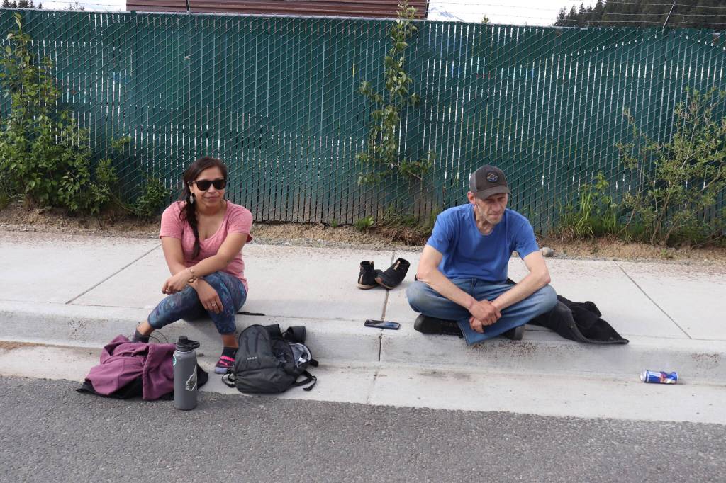 Jasmine White and Tyler Johnson relax on a sidewalk on Teal Street on Sunday. Both were homeless, but have found housing through agencies operating on the street. (Jasz Garrett / Juneau Empire)