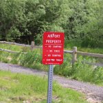 A sign near Juneau International Airport states camping and other activities are prohibited. However, some campers are on city land nearby. (Jasz Garrett / Juneau Empire)