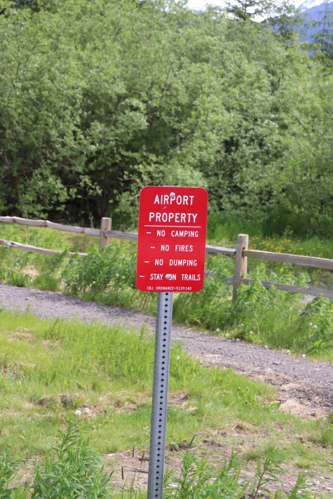 A sign near Juneau International Airport states camping and other activities are prohibited. However, some campers are on city land nearby. (Jasz Garrett / Juneau Empire)