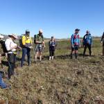 Competitors in the AlaskAcross 2024 race prepare to depart from Eagle Summit at 10 a.m. on June 8, 2024. From left are Bruno Grunau, Mark Ross, Forest Wagner, Mike Fisher, Sarah Hurkett, Clinton Brown, Tracie Curry and Curtis Henry. (Photo by Ned Rozell)