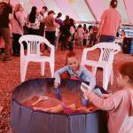 Alivia Workman, 5, and Aleijah Fulmer, 5, shift through sand looking for beads in the vendors tent during Juneau Gold Rush Days on Saturday at Savikko Park. (Mark Sabbatini / Juneau Empire)