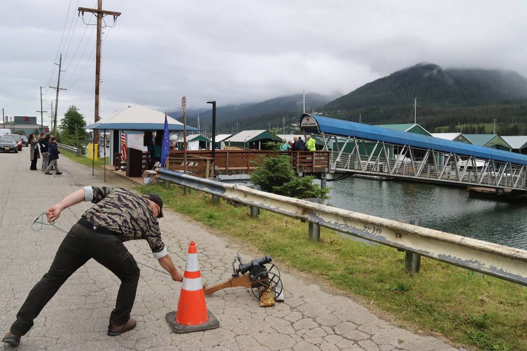 Chris Salazar fires a ceremonial cannon as dignitaries perform a ribbon cutting in the background during a ceremony celebrating the completion of the third of four stages of reconstruction of the 60-year-old Aurora Harbor. (Mark Sabbatini / Juneau Empire)