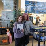 Alexis Griffin, a 2021 Thunder Mountain High School graduate, picks up a yearbook Monday from former teacher Janna Lelchuk. She participated in the yearbook for three years. (Jasz Garrett / Juneau Empire)