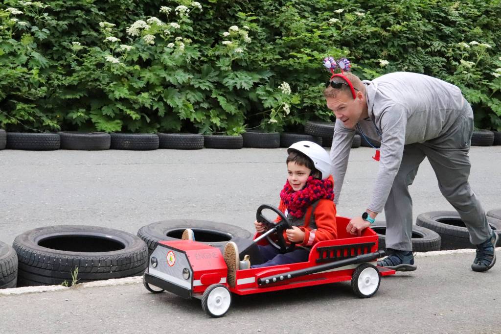 David Phillips pushes Russell Phillips back up the hill after passing the finish line at the trials of the soapbox challenge in Douglas on Wednesday. (Jasz Garrett / Juneau Empire)