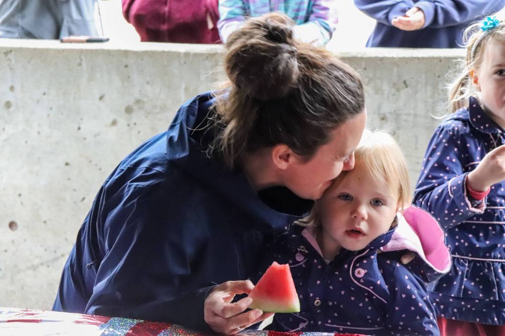 Ellis Pilcher, 2, gets a kiss from mom following her first attempt at the watermelon-eating contest at the Douglas Fourth of July Committees annual community picnic on Wednesday. (Jasz Garrett / Juneau Empire)