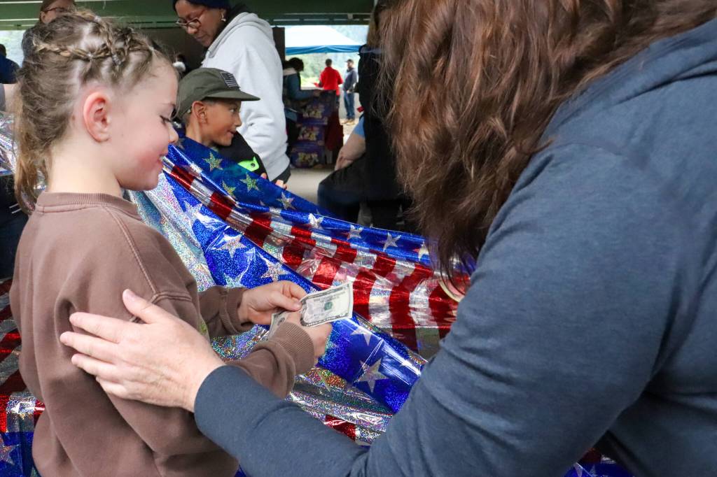 Perri Bardsley, 7, accepts her prize in the watermelon-eating contest at the Douglas Fourth of July Committees annual community picnic on Wednesday. Everyone receives $1 and a patriotic bracelet for participation, with a crisp $5 bill going to the winner. (Jasz Garrett / Juneau Empire)