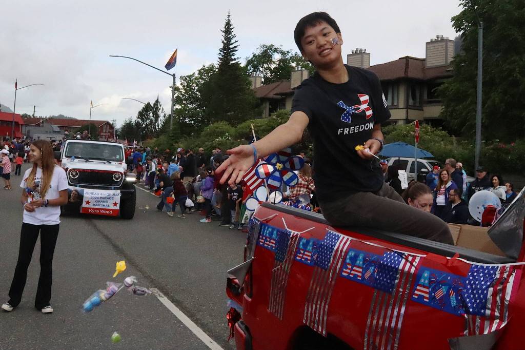 Mackenzie Lam, one of three grand marshals of Juneaus Fourth of July parade, passes out candy from the back of a truck on Thursday. (Mark Sabbatini / Juneau Empire)
