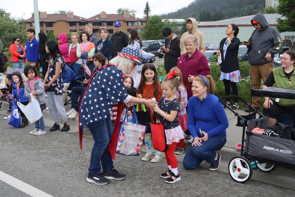 Molly McCormick (center), grand marshal of the Douglas Fourth of July parade, hands a ball to Stella Brooks, 4, during Juneaus Fourth of July parade Thursday morning before the afternoon parade in Douglas. (Mark Sabbatini / Juneau Empire)