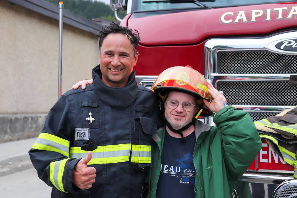 Joel Symons borrows Capital City Fire/Rescue Captain Jayme Johns helmet on July 4. (Jasz Garrett / Juneau Empire)
