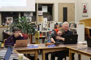 Juneau Board of Education President Deedie Sorensen (left) and Vice President Emil Mackey, holding his son Emil Mackey IV, listen to discussion about next years budget for the school district during a meeting March 14 at Juneau-Douglas High School: Yadaa.at Kalé. Recall votes for both board members were certified this week for the Oct. 1 municipal election ballot. (Mark Sabbatini / Juneau Empire file photo)