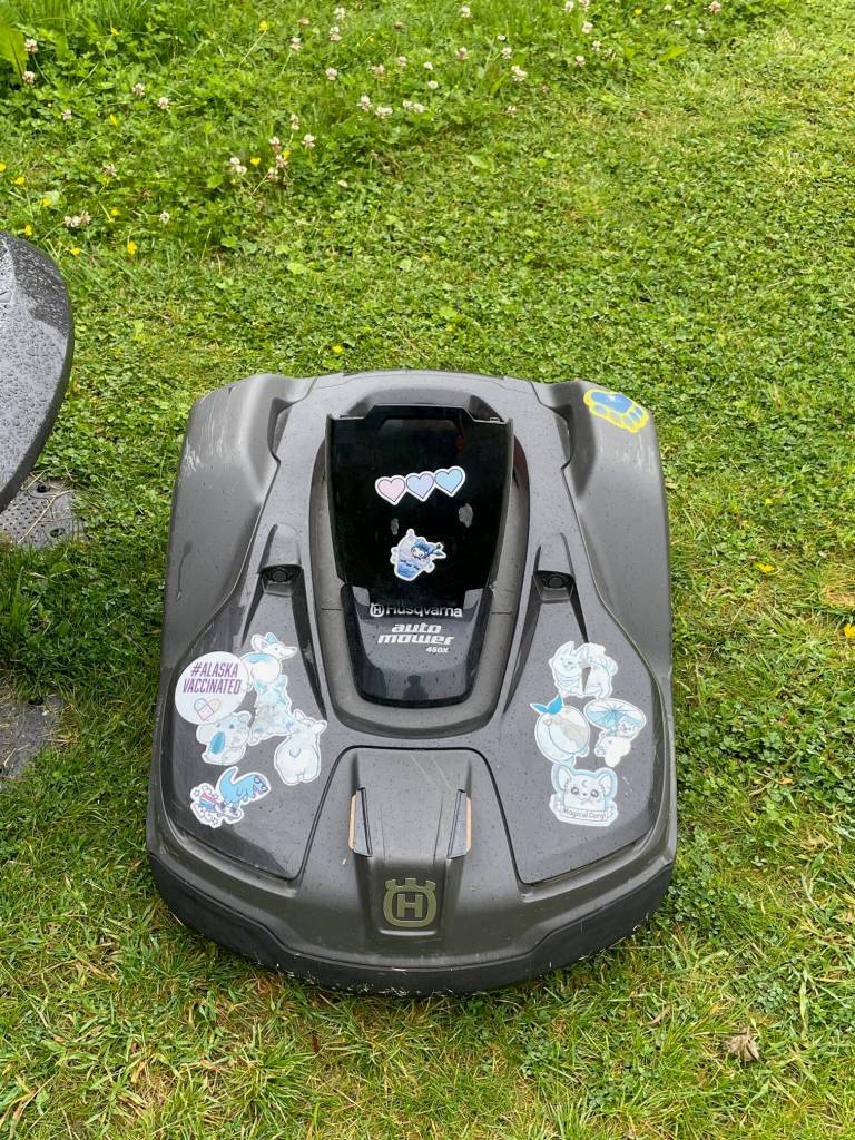 A Husqvarna automated mower operated by the school district is adorned with cheerful stickers children applied to the machine. (Laurie Craig / Juneau Empire)