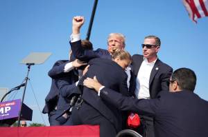 Former President Donald Trump is surrounded by Secret Service agents at a campaign rally in Butler, Pa, on Saturday. Trump was rushed off stage at rally after sounds like shots; the former president was escorted into his motorcade at his rally in Butler, Pa., a rural town about an hour north of Pittsburgh. (Doug Mills/The New York Times)