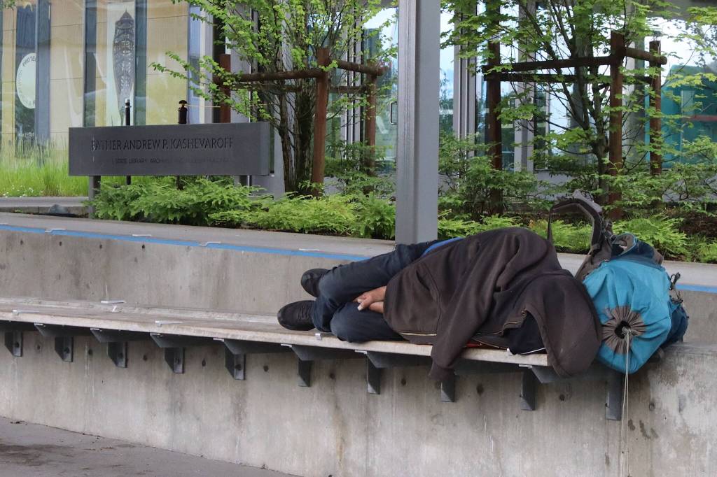 A person experiencing homelessness sleeps under the shelter outside the Alaska State Museum on the morning of July 4. (Mark Sabbatini / Juneau Empire file photo)