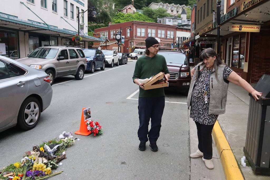 A passerby offers pizza to Patricia Allen, a friend of Steven Kissack, as she watches over a memorial for him at the spot where he was fatally shot by police on Monday. (Mark Sabbatini / Juneau Empire)